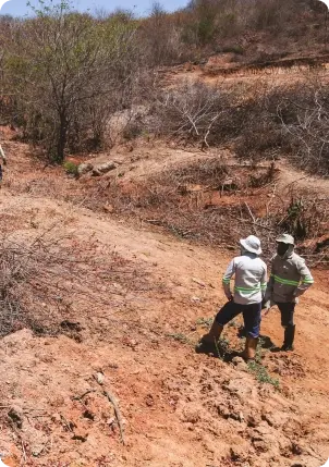 Dois técnicos da Cabugi caminhando em terreno de solo avermelhado