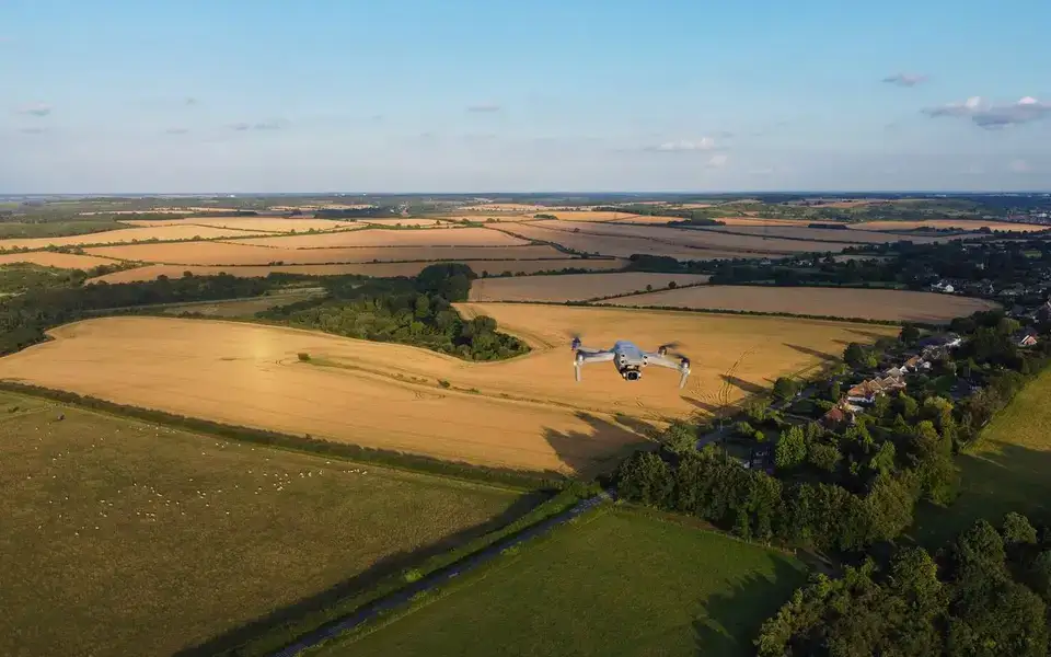 Drone sobrevoando uma grande área de campos abertos ao entardecer